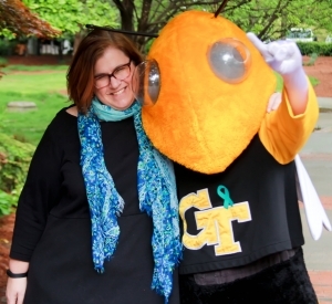 woman with brown hair and glasses hugging Georgia Tech's mascot, Buzz